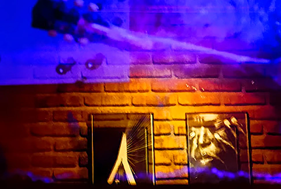 Fotografia de Ricardo Laf na Região Centro-Sul de BH, exibindo o reflexo de um contrabaixo no vidro em primeiro plano sobre o ambiente de um bar com tijolos.