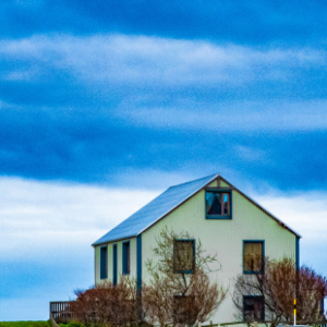 Fotografia autoral de Ricardo Laf mostrando uma casa isolada em uma paisagem verdejante e montanhosa nos Fiordes Ocidentais da Islândia.