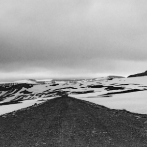 Fotografia autoral de Ricardo Laf em preto e branco mostrando o término de uma estrada de terra que encontra uma barreira de gelo e montanhas em Ísafjarðarbær, Islândia.