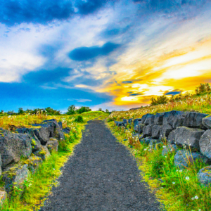 Fotografia autoral de Ricardo Laf mostrando um caminho de pedras vulcânicas que leva ao alto de Hamarinn em Hafnarfjörður, Islândia, sob a luz do sol da meia-noite.