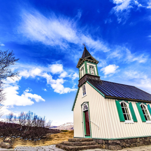 Fotografia de Ricardo Laf apresentando a Igreja de Þingvallakirkja sob um céu azul dinâmico no Parque Nacional de Þingvellir, Islândia.