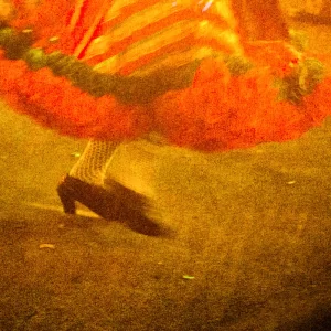 Fotografia de Ricardo Laf capturando o movimento de uma dançarina de quadrilha no Arraial de Belô, na Praça da Estação, com tons quentes e foco no rastro do vestido.