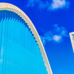 Fotografia autoral de Ricardo Laf mostrando um detalhe das curvas da Igreja São Francisco de Assis na Pampulha, com destaque para o azul da estrutura e o campanário contra o céu.