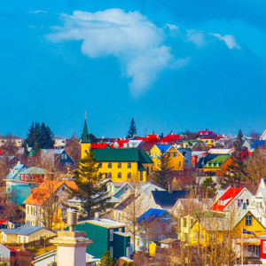 Fotografia de Ricardo Laf capturando a vista de Hafnarfjörður, na Islândia, através de uma janela, mostrando a arquitetura colorida sob um céu azul.