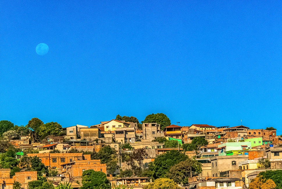 Vista panorâmica da região nordeste de Belo Horizonte, mostrando a densidade de casas e prédios sob um céu azul claro, fotografia de Ricardo Laf.