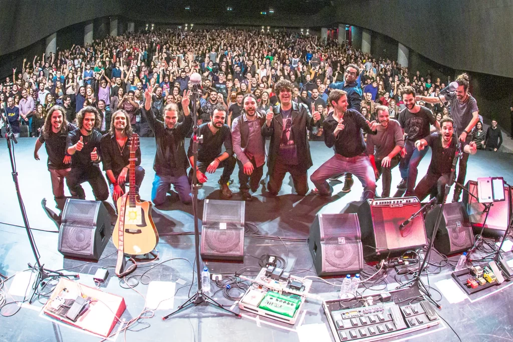 Todos os músicos da Orquestra Mineira de Rock à frente do palco, sorrindo para o público ao final do show.
