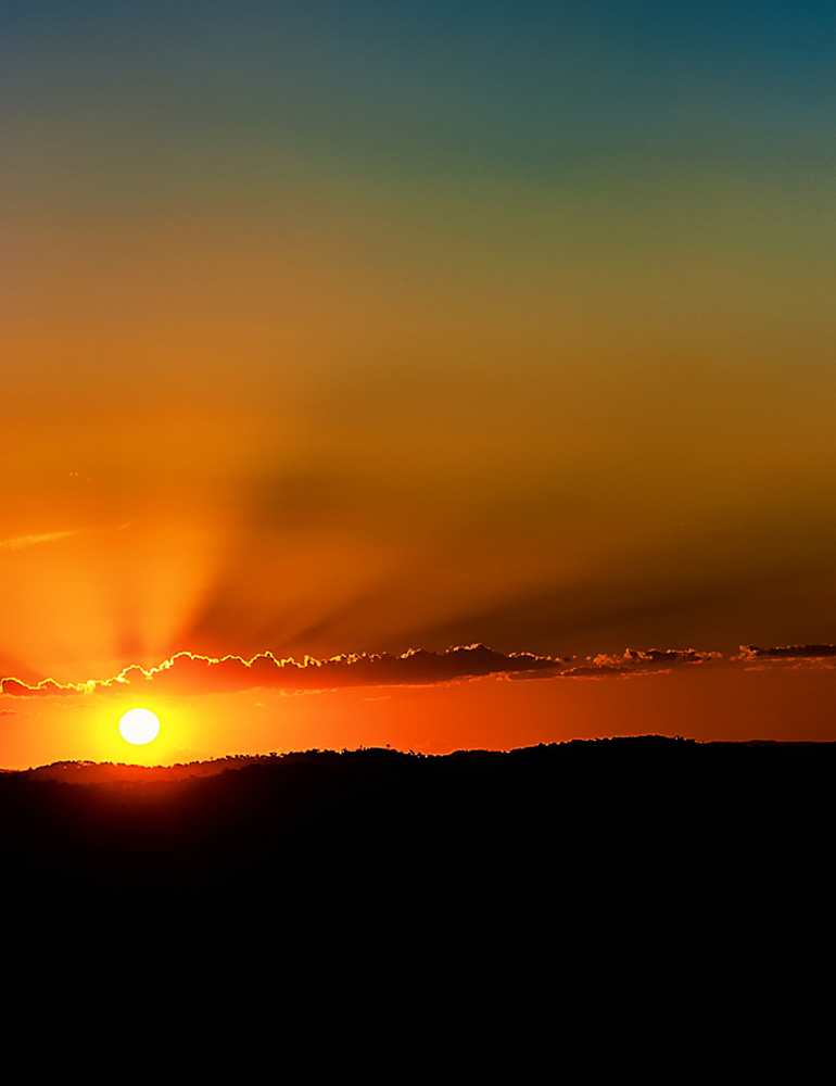 Fotografia de Ricardo Laf apresentando o pôr do sol da Serra da Moeda em Minas Gerais, com a vegetação rasteira e o solo rochoso em destaque sob a luz do fim de tarde.