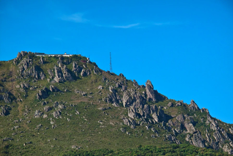 Fotografia de Ricardo Laf destacando o relevo rochoso e a vegetação rasteira da Serra da Piedade em Caeté, Minas Gerais, sob um céu azul intenso.