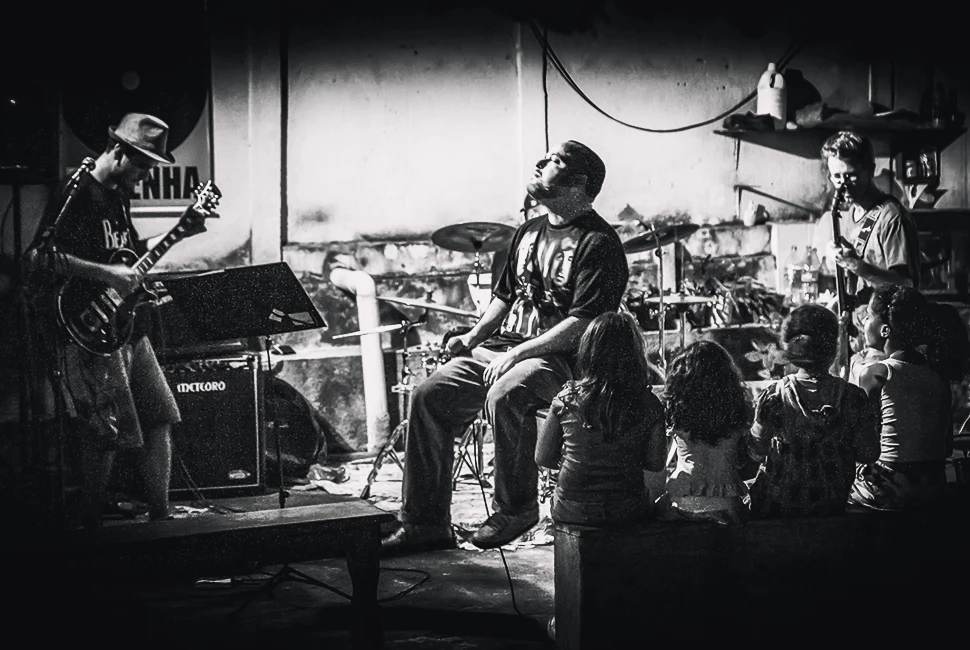 Fotografia autoral em preto e branco de Ricardo Laf capturando a performance de "DaPenha" no espetáculo "Da Troça do Trampo" em um palco na região nordeste de Belo Horizonte.