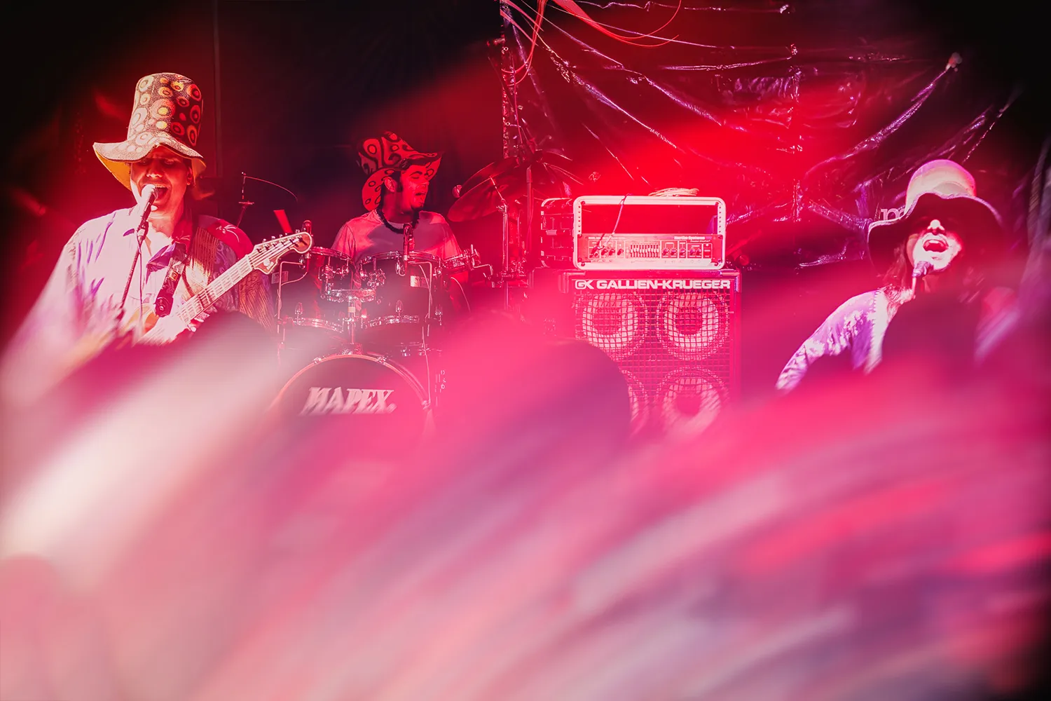 Fotografia de Ricardo Laf capturando a banda Somba em um momento de alta intensidade performática, imersa em luzes vermelhas que enfatizam a dramaticidade e a vibração do espetáculo.