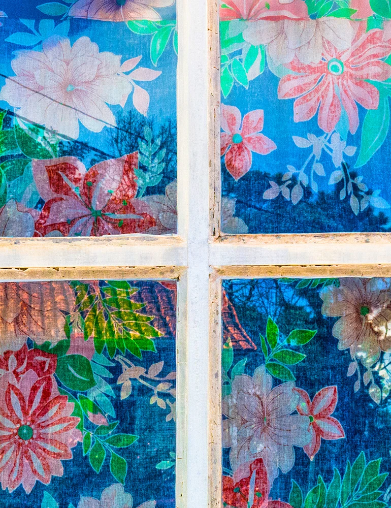 Fotografia autoral de Ricardo Laf mostrando uma composição de janelas de madeira com cortinas de estampas florais coloridas em tons de azul, rosa e amarelo.