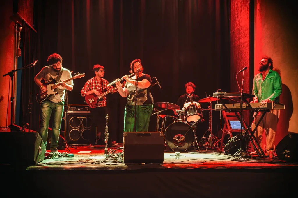 Fotografia de Ricardo Laf registando a harmonia coletiva de Juliana Perdigão e sua banda, com destaque para a profundidade do palco e a atmosfera envolvente da luz.