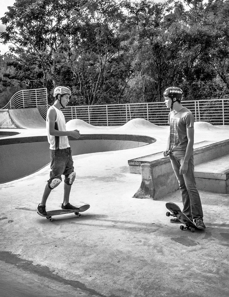 Dois jovens dialogam antes das próximas aventuras de skate na borda de uma pista de skate no Parque Lagoa do Nado, fotografia de Ricardo Laf.