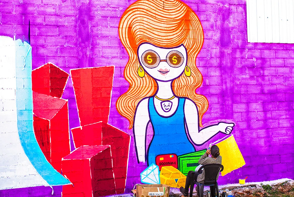 Um artista observa seu próprio mural de arte urbana colorido em uma parede na região norte de Belo Horizonte, fotografia de Ricardo Laf.