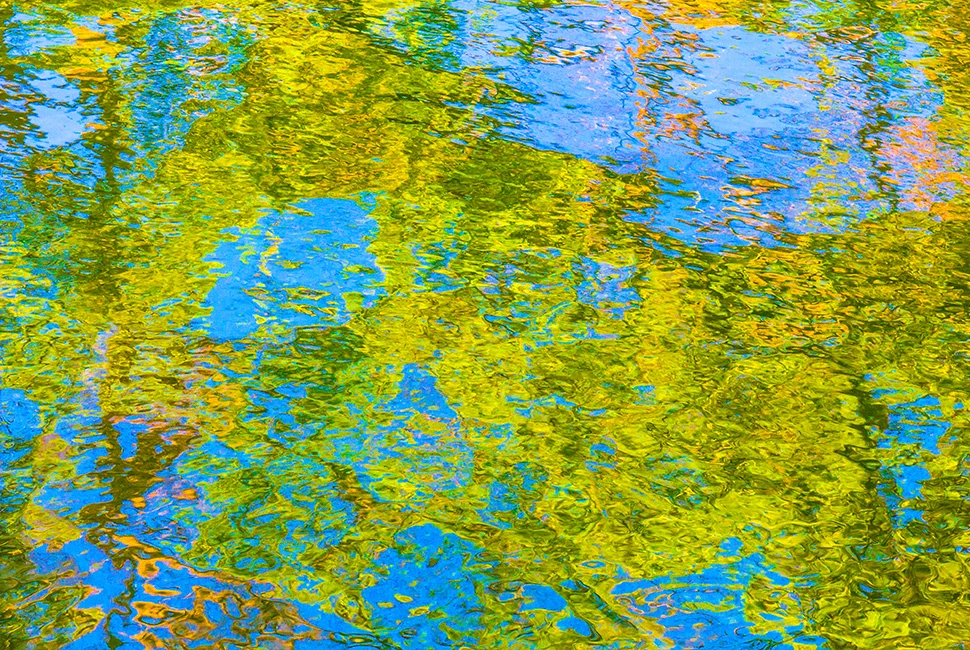 Fotografia abstrata da superfície da água em tons de verde e dourado, com reflexos da vegetação e ondulações suaves, capturada no Parque Municipal de Belo Horizonte.