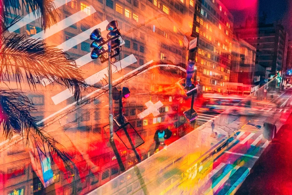 Fotografia colorida com técnica de dupla exposição de Ricardo Laf, capturando o movimento noturno e os rastros luminosos em tons de vermelho e azul no centro urbano de Belo Horizonte.