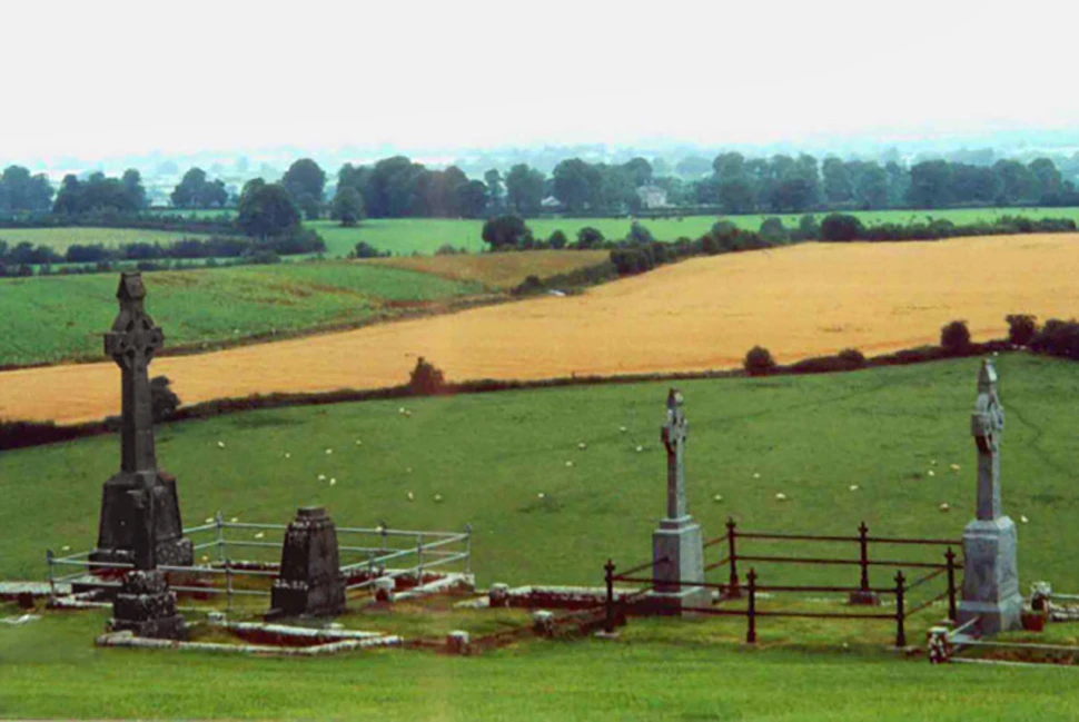 Lápides e monumentos de pedra em um cemitério medieval na Irlanda, sob uma luz melancólica e histórica.