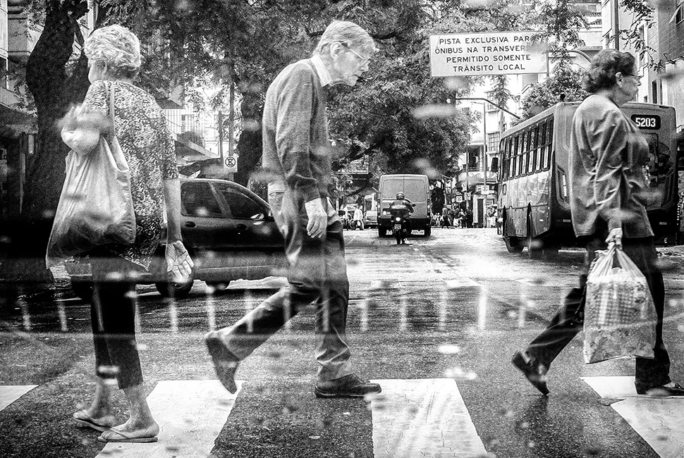 Fotografia de rua em Belo Horizonte mostrando pedestres cruzando a avenida no centro da cidade, com foco no movimento e na arquitetura urbana, por Ricardo Laf.