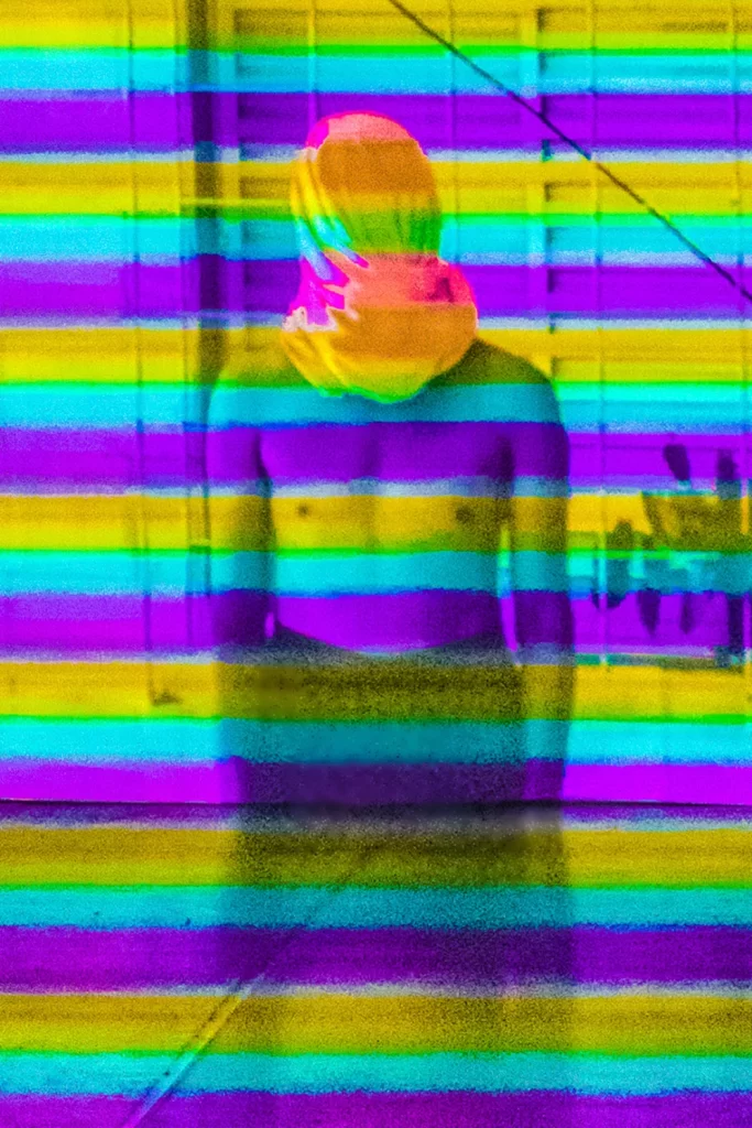 Fotografia de Ricardo Laf exibindo um corpo fragmentado por linhas horizontais coloridas e vibrantes, simulando uma interferência visual em uma vitrine em Belo Horizonte.