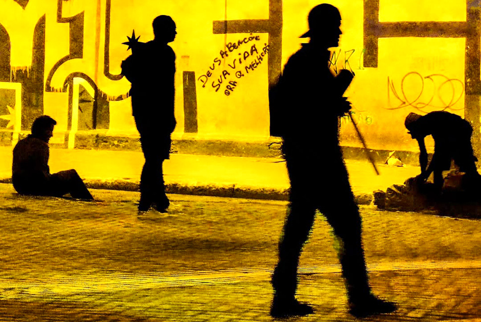 Foto de Ricardo Laf capturada de dentro de um veículo no baixo centro de Belo Horizonte. No segundo plano, um muro exibe a pichação: "Que Deus abençoe sua vida. Ore q melhora", registrando a espiritualidade urbana.