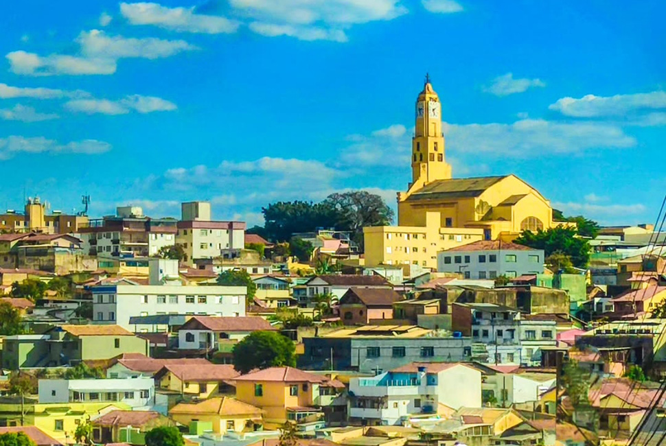 Fotografia de Ricardo Laf da Igreja São Francisco das Chagas, localizada no topo de um morro na região Noroeste de Belo Horizonte. A imagem destaca a arquitetura da igreja fundada em 1929 contra um céu azul limpo.