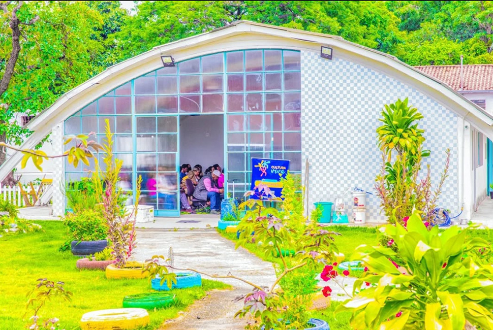 Fotografia de Ricardo Laf da fachada do edifício que abriga o CENARAB (Centro Nacional de Africanidade e Resistência Afro-brasileira), na região Oeste de Belo Horizonte. A imagem mostra a entrada da instituição cercada por vegetação.