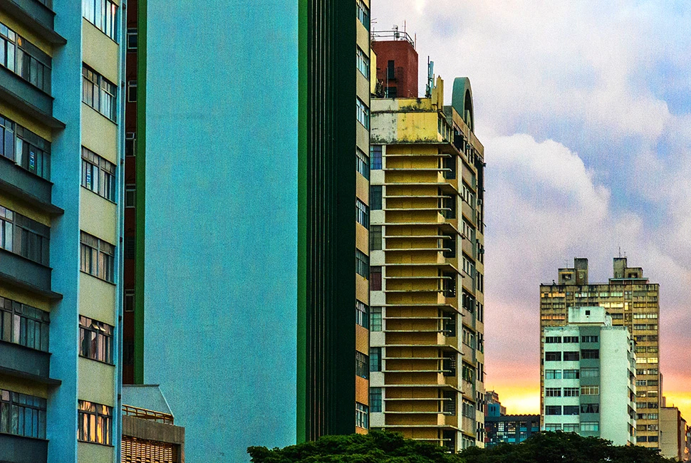 Fotografia de Ricardo Laf mostrando uma vista da região central de Belo Horizonte, com destaque para edifícios altos sob um céu claro com nuvens leves ao entardecer.