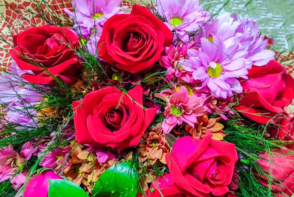 Fotografia de Ricardo Laf destacando um arranjo de rosas cor-de-rosa intensas com detalhes das pétalas e folhagens verdes em composição cerrada.