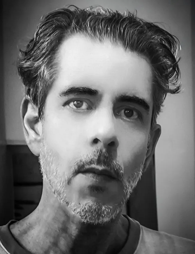 Autorretrato em preto e branco de Ricardo Laf, fotógrafo e jornalista, em ambiente introspectivo.