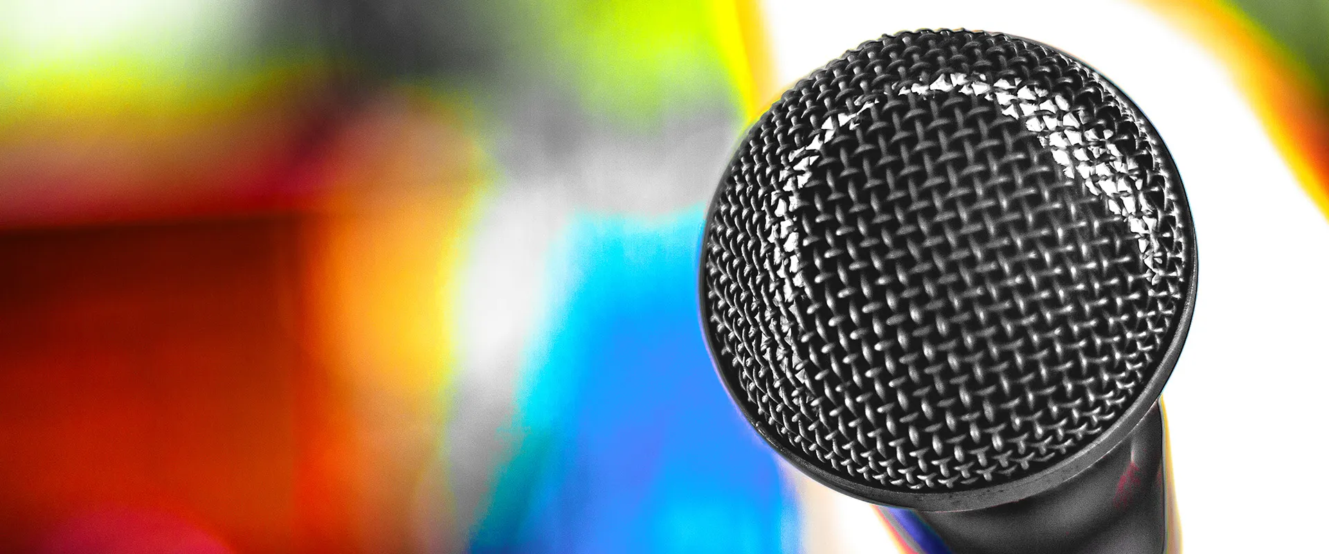 Fotografia autoral de Ricardo Laf em close-up de um microfone detalhado, capturando a textura da malha metálica contra um fundo de cores vibrantes e luz estourada.