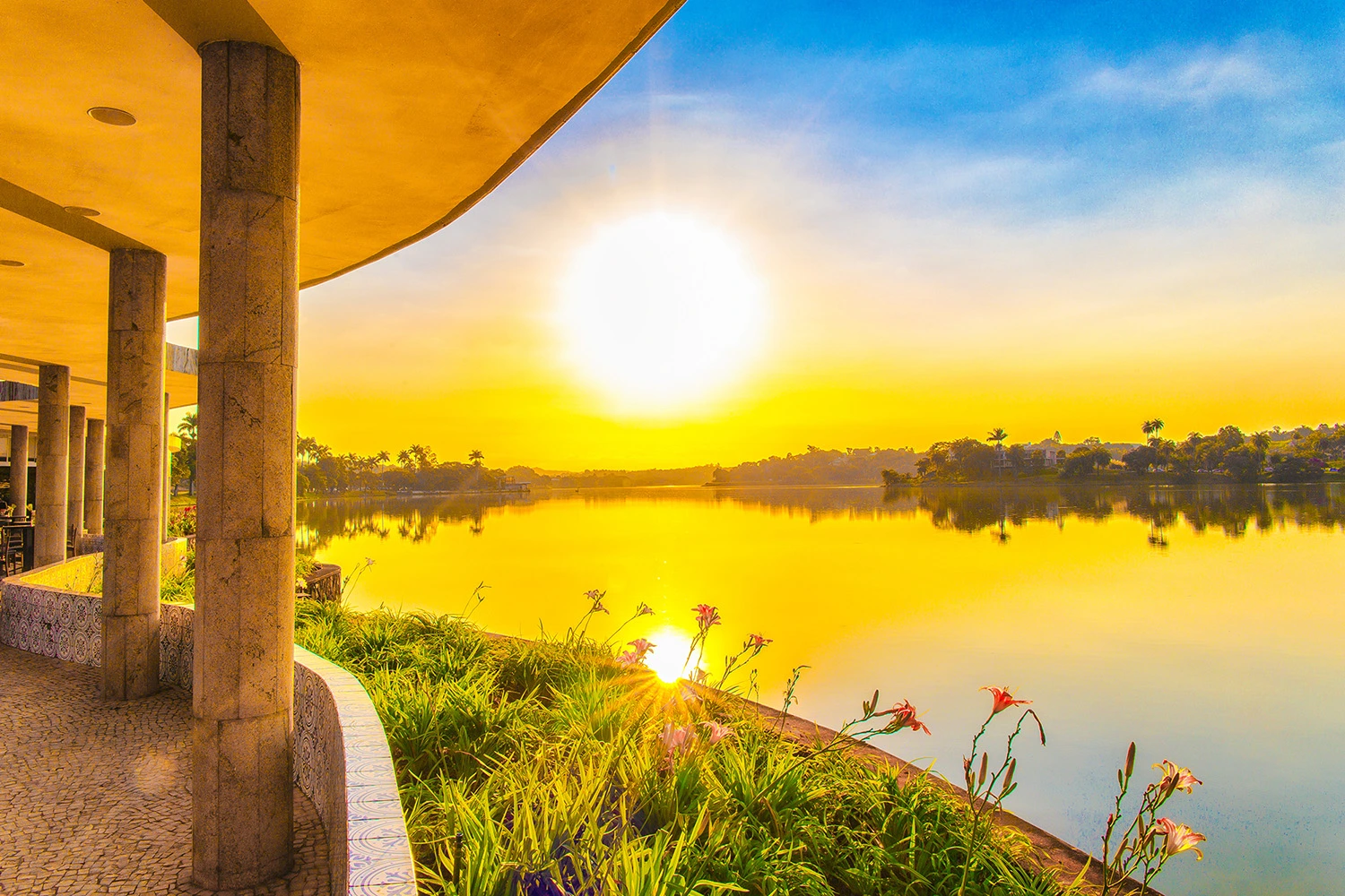 Vista externa da Casa do Baile na Lagoa da Pampulha ao pôr do sol, destacando as curvas da arquitetura modernista de Oscar Niemeyer e o reflexo na água em Belo Horizonte.