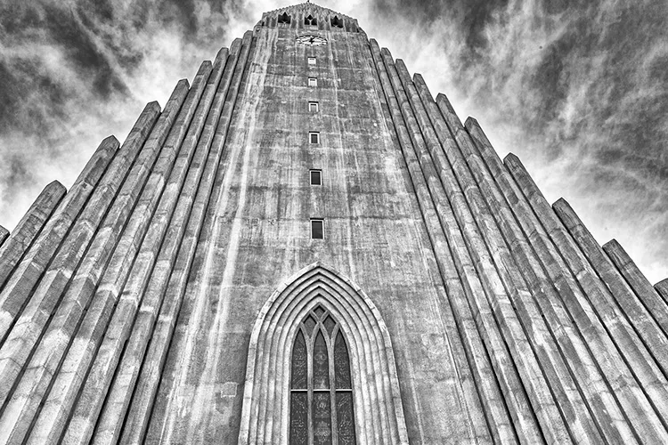 Vista em ângulo baixo da fachada em concreto da igreja Hallgrímskirkja em Reykjavík, destacando suas colunas verticais inspiradas em formações de basalto.
