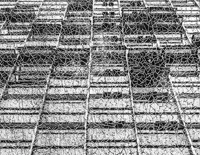 Fotografia gráfica e abstrata em preto e branco destacando a textura trincada de uma superfície de acrílico com a fachada de um prédio ao fundo no centro de Belo Horizonte.