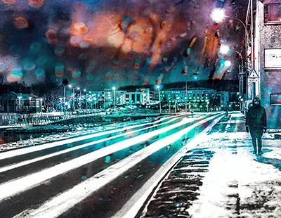 Fotopintura urbana de uma rua sob chuva em Hafnarfjörður, Islândia, com pedestre caminhando e reflexos luminosos no asfalto molhado.