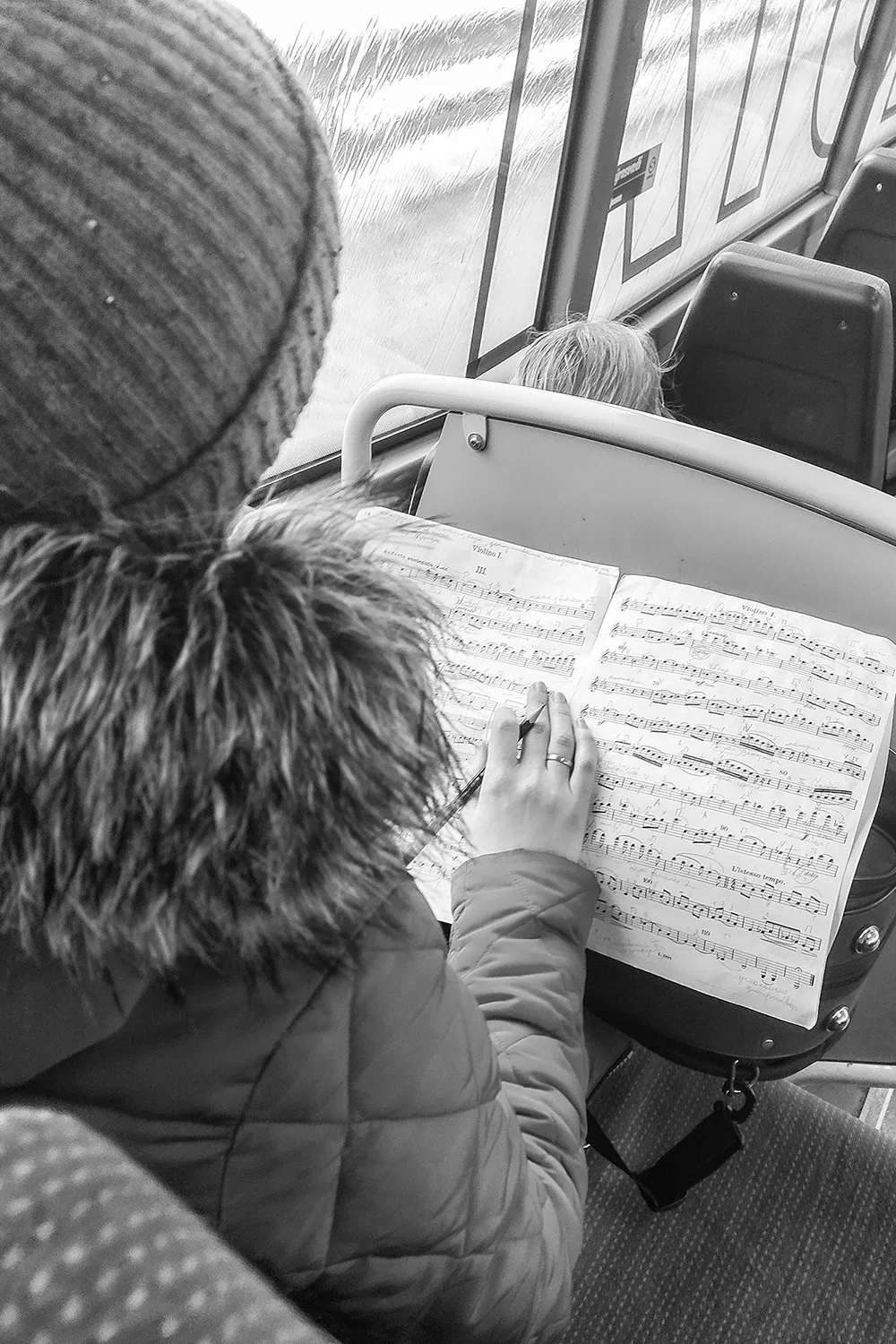 Fotografia em preto e branco de passageira lendo partitura de música dentro de ônibus em Kópavogur na Islândia por Ricardo Laf.