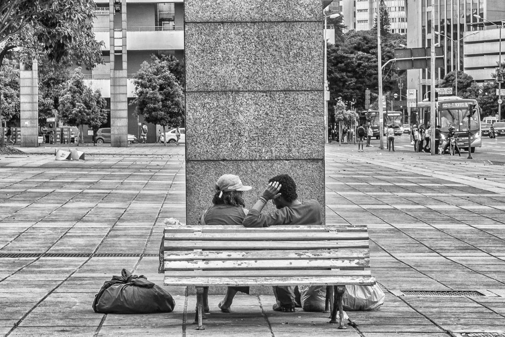 An Instant of Affection in the City - Fotografia em preto e branco de um casal sentado em um banco de madeira na Praça da Estação em Belo Horizonte. Foto na seleção Avançada no Concurso "The Shape of a Moment" - Exposure Photo Gallery