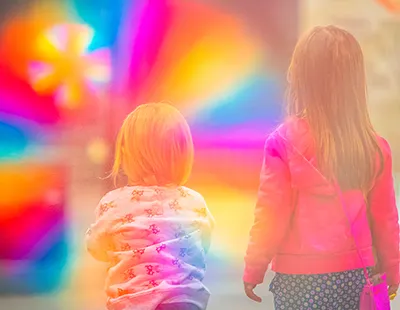 Fotopintura vibrante de figuras observando uma aura luminosa e multicolorida que forma um portal cromático.