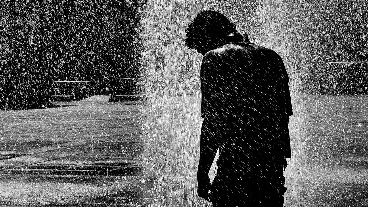 Fotografia em preto e branco de figura humana solitária sob cortina de água na Praça da Estação em Belo Horizonte por Ricardo Laf, chancelada com Reconhecimento Especial na Exposure Photo Gallery.